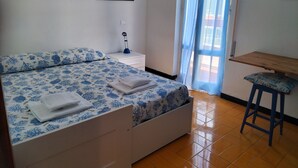 Ein Schlafzimmer mit Bett, Nachttisch, Schreibtisch und einem Fenster mit Vorhängen.