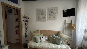 A living room with a sofa, a floor lamp, and two wall-mounted paintings. - Dume Cosy Apt - Central - Near the beach with A.C. (Monterosso al Mare)