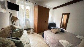 A room with a bed, a sofa, a chair, a TV, and a window with curtains. - Dume Cosy Apt - Central - Near the beach with A.C. (Monterosso al Mare)