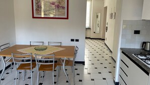 A dining area with a wooden table and chairs, a kitchen with a tiled backsplash, and a hallway with a mirror and framed artwork.