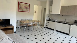 A compact kitchen with a dining area, a television, and a bed.