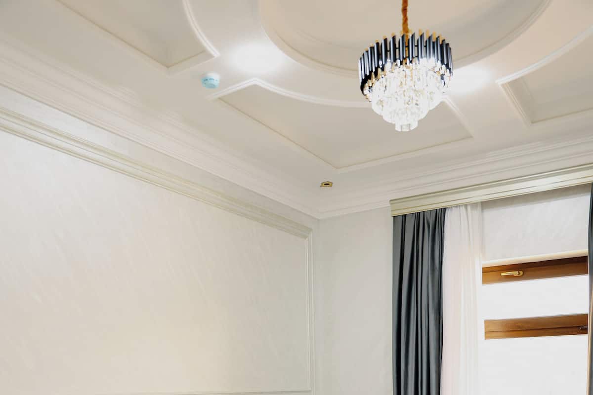 A hotel room with two beds, a chandelier, and a window with curtains.