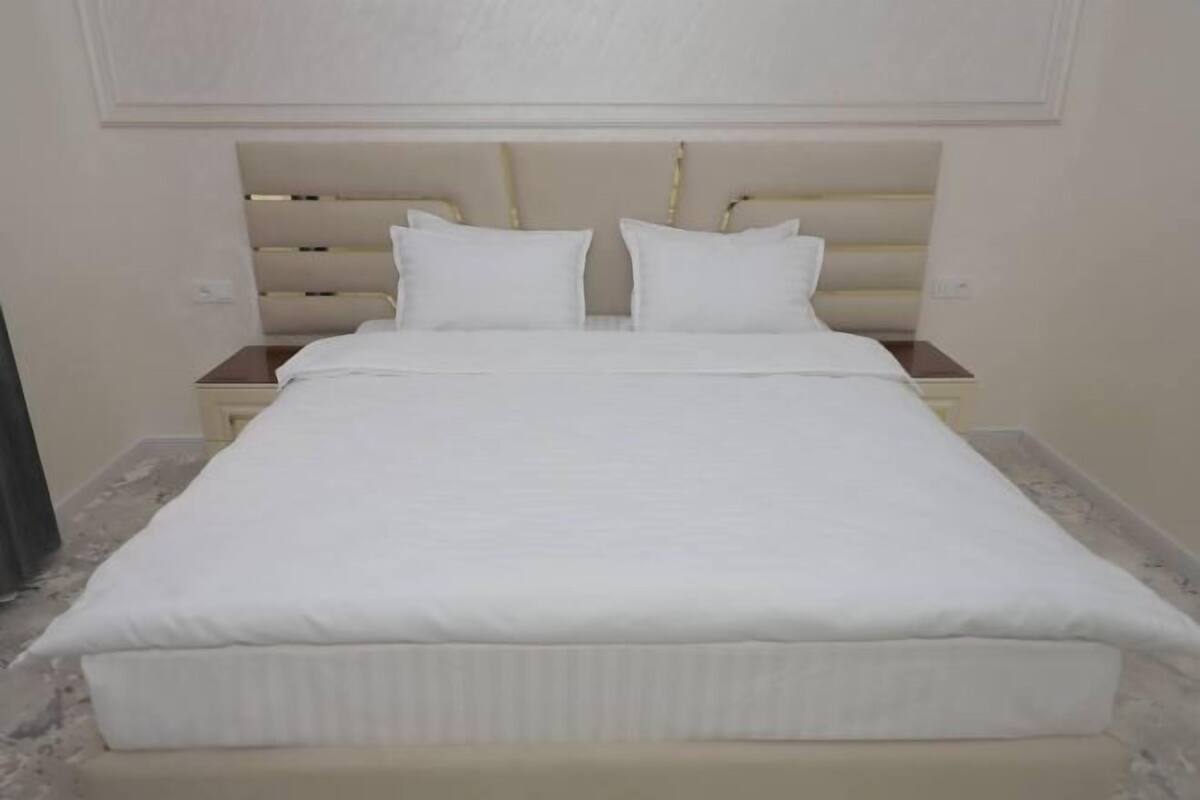 A bed with a headboard, two bedside tables, and a marble floor.
