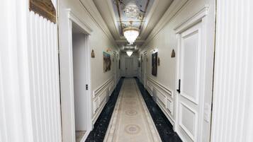 Un pasillo de hotel con piso de mármol, paredes blancas y un candelabro.