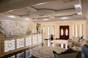 A spacious lobby with a round carpet, elegant furniture, and decorative wall art.