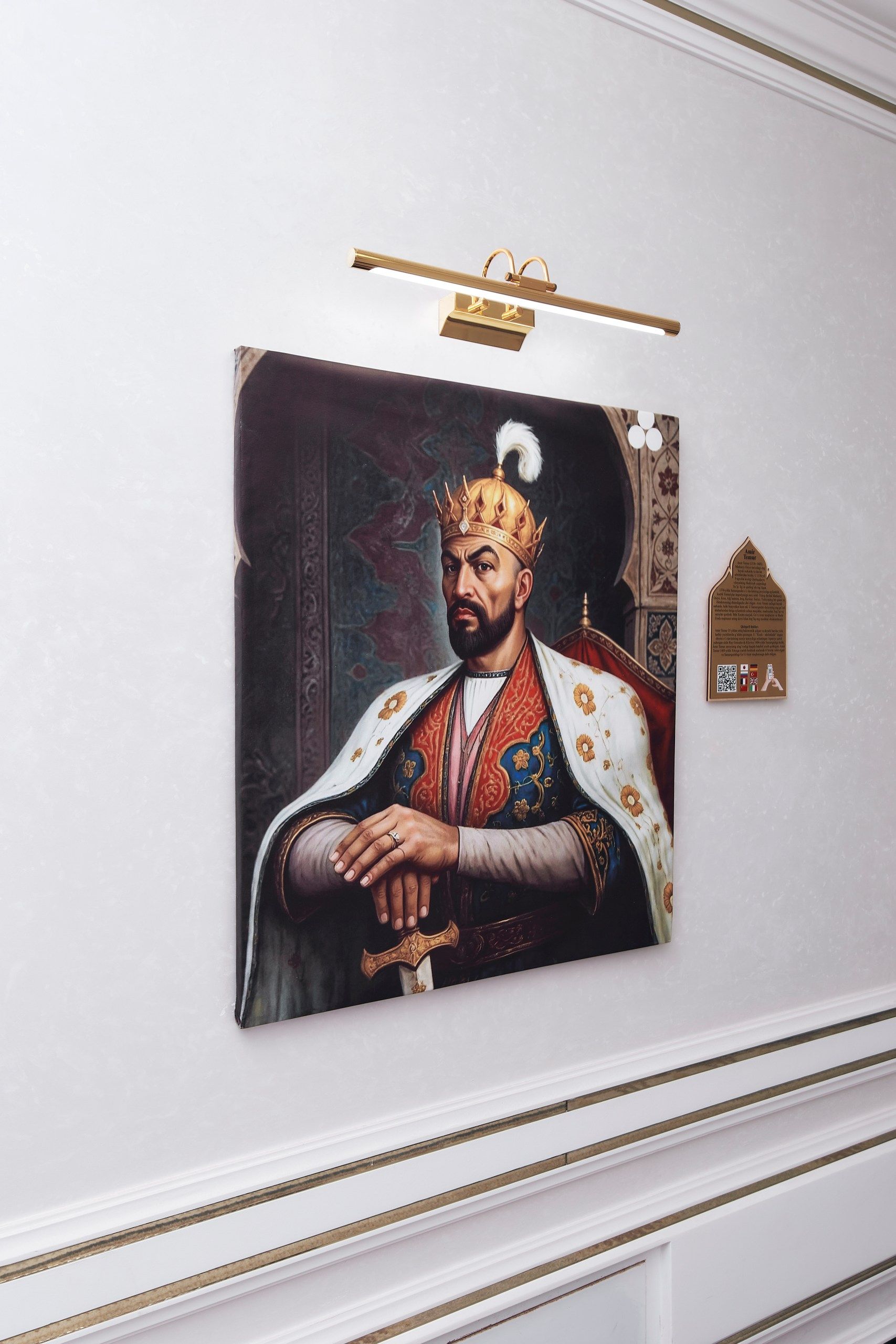 A framed portrait of a historical figure with a crown, a sword, and a nameplate on the wall.