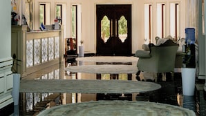 A grand room with a chandelier, a large mirror, and a round table.
