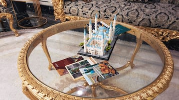 Une table basse ronde en verre avec un cadre doré, une maquette miniature d’une mosquée et plusieurs brochures.
