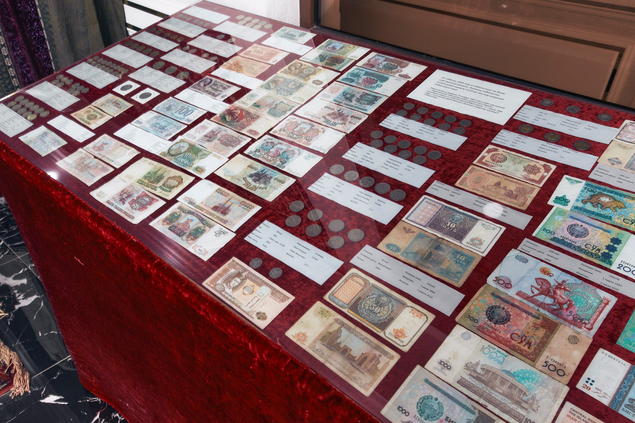 Een overzicht van verschillende bankbiljetten en munten op een tafel bekleed met rode fluweel.