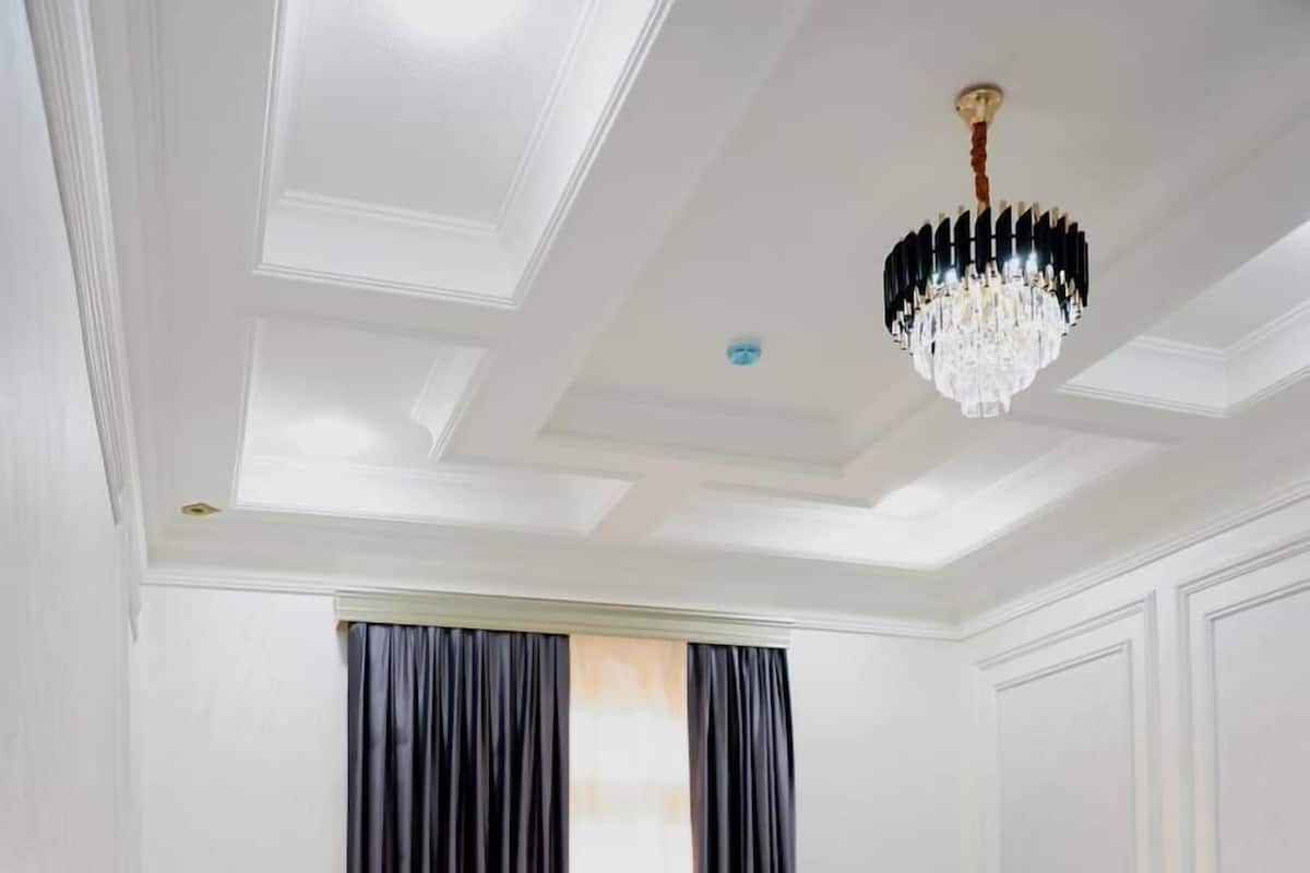 A hotel room with a bed, a desk, and a chandelier.