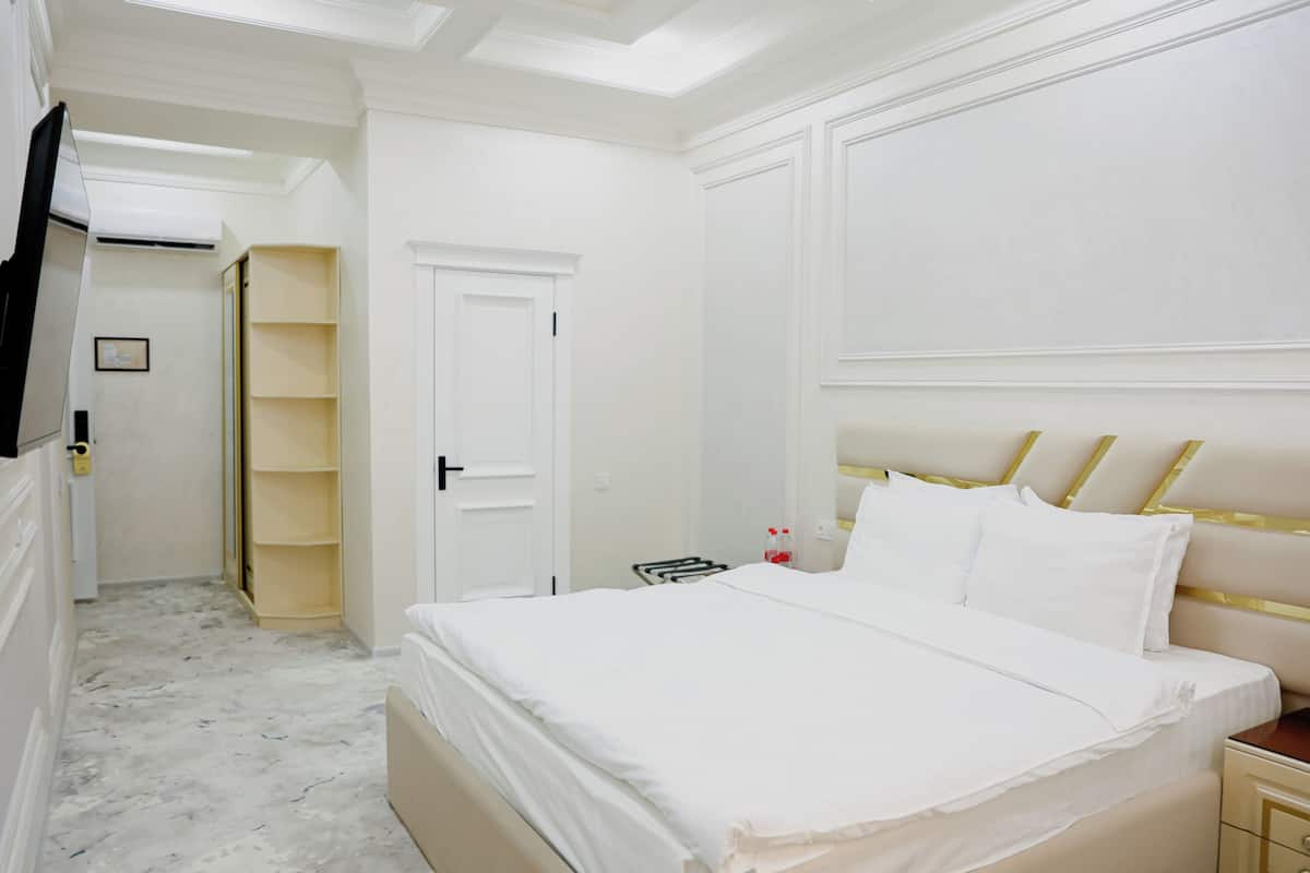 A hotel room with a large bed, a bedside table, a wardrobe, and a television.