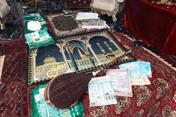 Un tapete de oración con diseños intrincados, una alfombra de oración tradicional y una losa de madera para oración sobre una alfombra estampada.