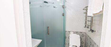 Un baño moderno con ducha de vidrio, inodoro blanco y azulejos estampados.