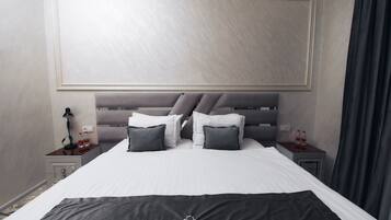 A hotel room with a large bed, a headboard, two bedside tables, and a nightstand.
