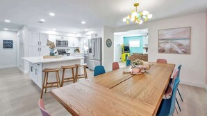 Une cuisine moderne avec des meubles blancs, une table à manger en bois et des tabourets de bar.