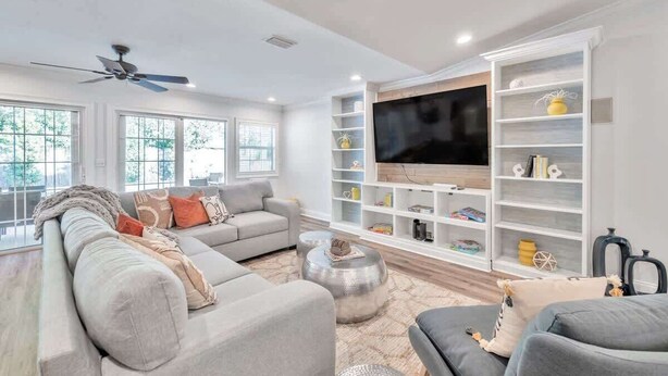 A modern living room with a sofa, coffee table, and a TV wall unit. - Heated Pool, Stylish Home | Grand Cypress Retreat (Clearwater)