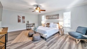 A bedroom with a bed, a desk, a chair, a sofa, and a ceiling fan. - Heated Pool, Stylish Home | Grand Cypress Retreat (Clearwater)