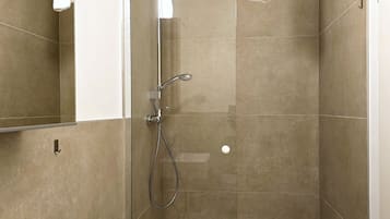 Une salle de bain moderne avec une douche à parois de verre, un lavabo blanc et un grand miroir.