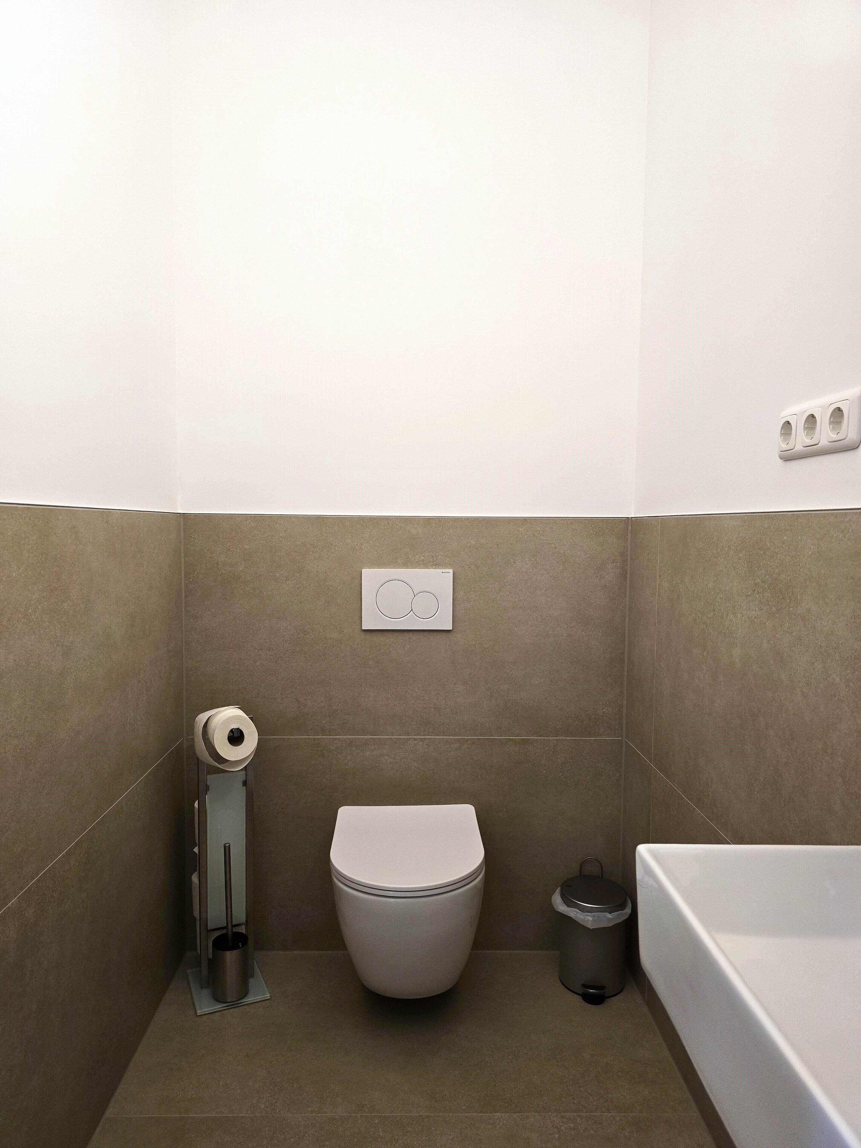 Une petite salle de bain avec des toilettes, une poubelle et une baignoire.