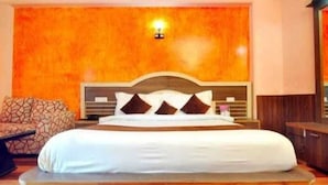 A bedroom with a large bed, a headboard, and a wall-mounted light fixture. - Royal Grand By Skua World  (Manali)
