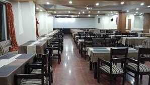 A spacious dining area with multiple tables and chairs, arranged in rows. - Royal Grand By Skua World  (Manali)