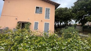 A two-story building with a peach-colored facade, three windows with shutters, and a small entrance. - Nociarelle Cottage (Nociarelle-Scarpiello)