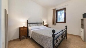 A bedroom with a bed, bedside tables, a window with curtains, and a view of the outside. - Nociarelle Cottage (Nociarelle-Scarpiello)