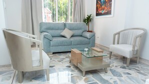 A living room with a light blue sofa, a glass coffee table, a white armchair, and a stone-patterned floor. - Lovely 4-bed House in Palmira Valle del Cauca (Palmira)