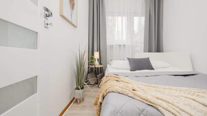 Quarto moderno com cama, mesa de cabeceira, luminária e janela com cortinas.