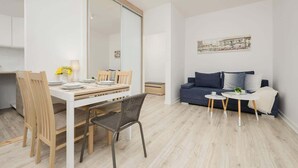 Uma sala de estar moderna com área de jantar, um sofá e uma mesinha com uma planta.