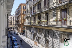Un vicolo stretto fiancheggiato da edifici a più piani, alcuni con balconi e piante in vaso.