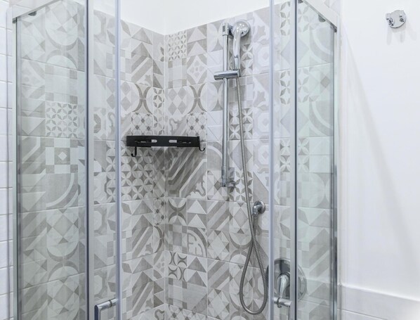 A glass-enclosed shower with a geometric tile pattern on the walls. - Hotiday Room Collection - Napoli Sant’Arcangelo  (Naples)