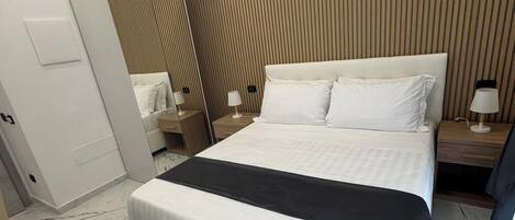 A modern hotel room with a large bed, a wooden panel wall, and a marble floor.