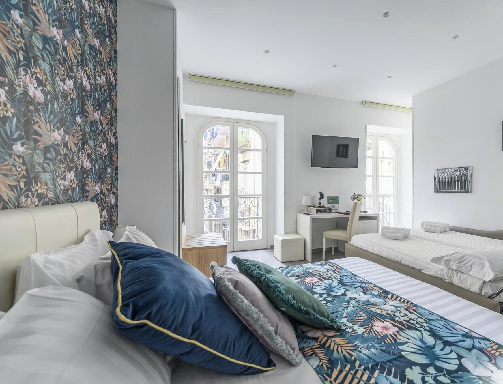 Habitación de hotel con cama, escritorio, televisor y ventana con vista a la ciudad.