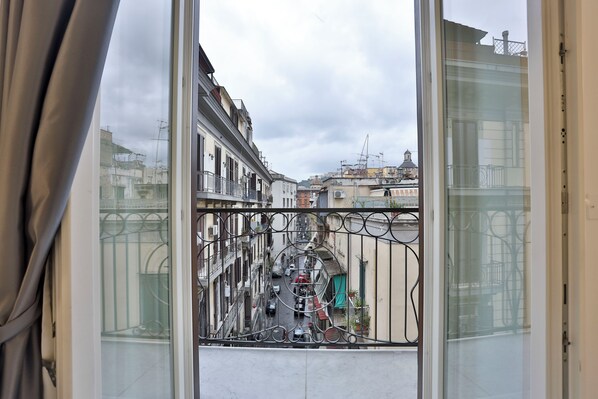 A view from a balcony with a metal railing, overlooking a narrow street with buildings and parked cars. - Hotiday Room Collection - Napoli Sant’Arcangelo  (Naples)