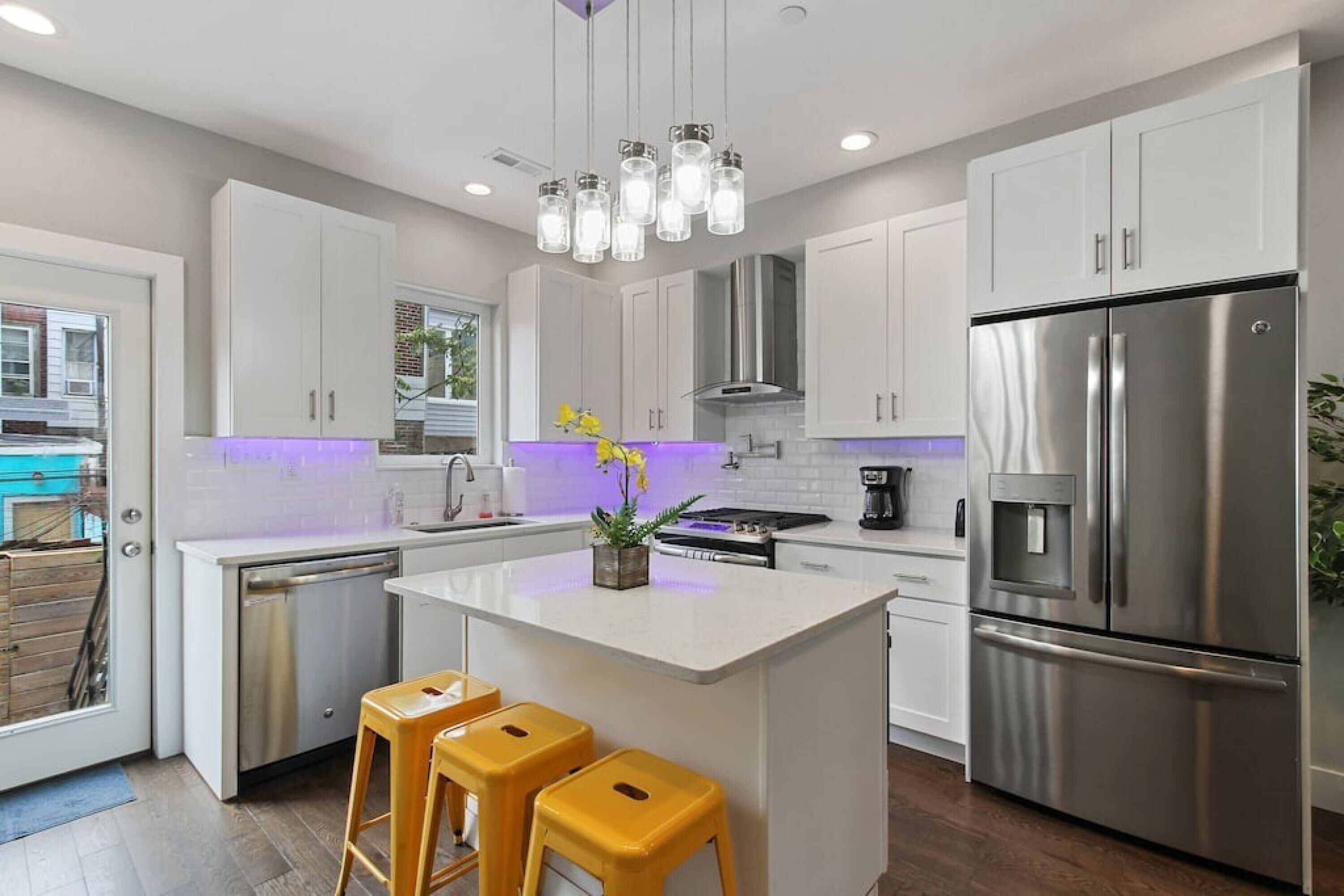 A modern kitchen with white cabinets, stainless steel appliances, and a central island with stools.