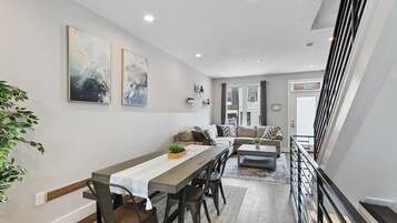 A modern living room with a dining area, featuring a sofa set, a coffee table, and a dining table with chairs.