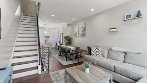 A modern living room with a staircase, a dining area, and a sofa. - Skyline Best Roofdeck Views 2 Miles Penn Chop (Philadelphia)