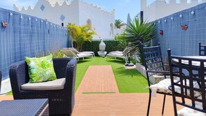 Un patio con sendero de madera, sillas de descanso y una estatua de Buda.