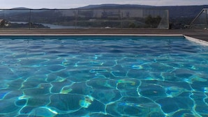Ein Schwimmbecken mit klarem, blauem Wasser und Blick auf Berge im Hintergrund.