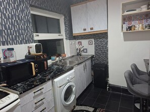 A compact kitchen with a washing machine, a microwave, and a sink. - Humuplace Sleeps 4 With Garden (Birmingham)
