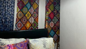 A bedroom with a bed, colorful patterned curtains, and a hanging light fixture. - Humuplace Sleeps 4 With Garden (Birmingham)