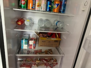 Geladeira com bebidas, lanches e uma seleção variada.