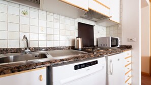 A kitchen with white cabinets, a stainless steel sink, a microwave, and a coffee maker. - Italianway - Bruni 2 (Bormio)