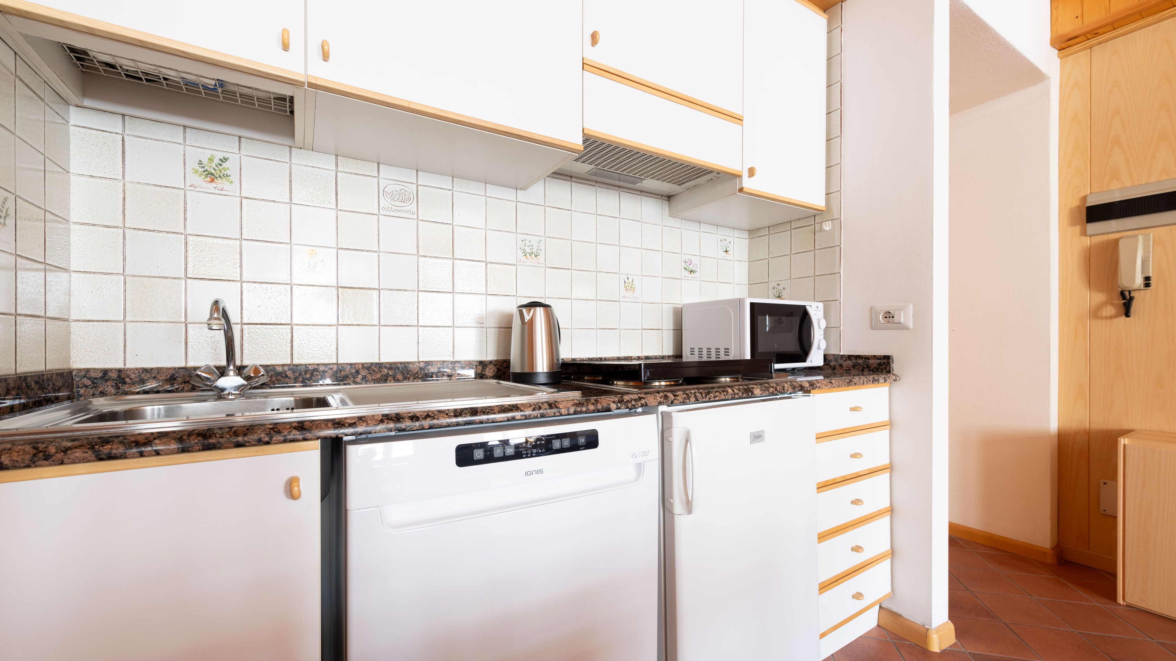 A compact kitchen with a dishwasher, a microwave, and a sink.