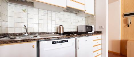 A compact kitchen with a dishwasher, a microwave, and a sink.