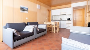 En hyggelig stue med sofa, spisebord og et køkkenområde.