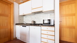 A compact kitchen with white cabinets, a built-in microwave, and a dishwasher. - Italianway - Bruni 2 (Bormio)