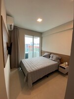 Habitación de hotel con cama, mesita de noche, televisor y ventana con vista a la ciudad.