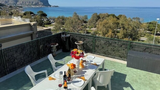 A dining table set outdoors with a view of the sea and mountains. - 2 Bedroom Apartment in PALERMO (PALERMO)